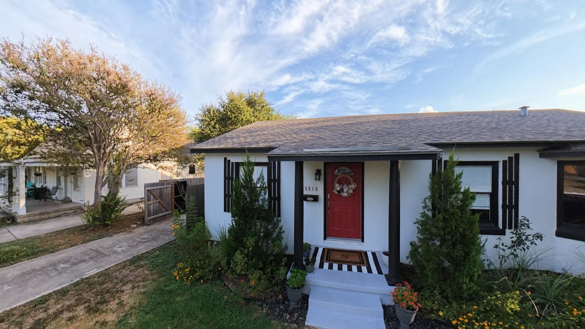 Front entrance of 2018 W Mulberry with white siding, dark shutters and a red door